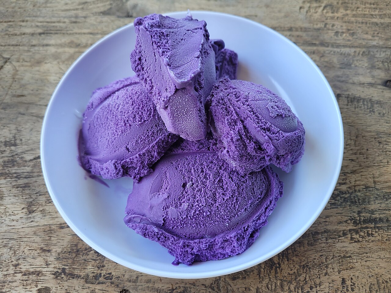 A bowl of vivid purple ube ice cream scoops
